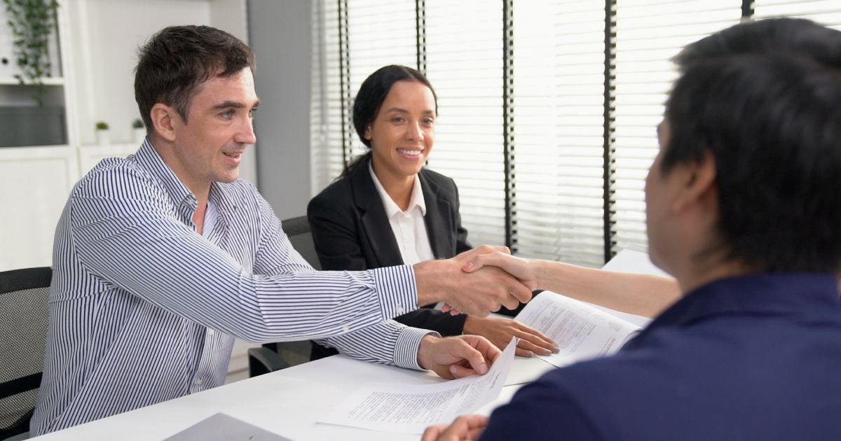 men shaking hands woman smiling doing business