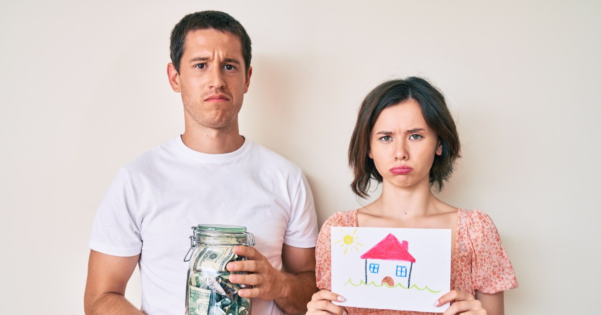 couple pouty look holding money and drawing of house
